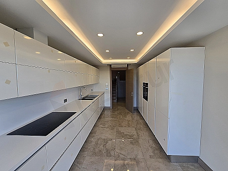 Modern tasarımlı, beyaz mutfak dolapları ve ankastre cihazlara sahip, aydınlık ve ferah mutfak.