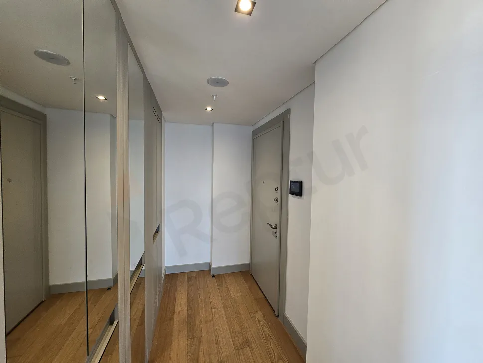 Modern bir dairenin geniş, aydınlık ve minimalist tasarımlı koridoru.