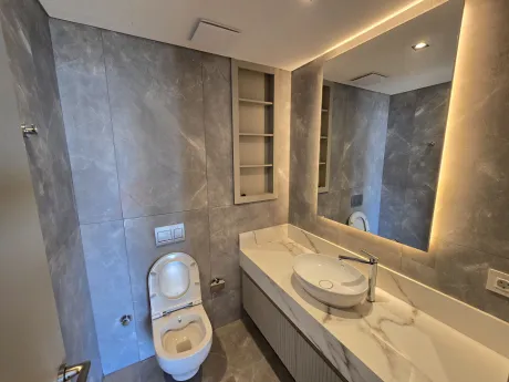 Modern tasarımlı, şık seramik ve armatürlerle donatılmış lüks bir banyo alanı.