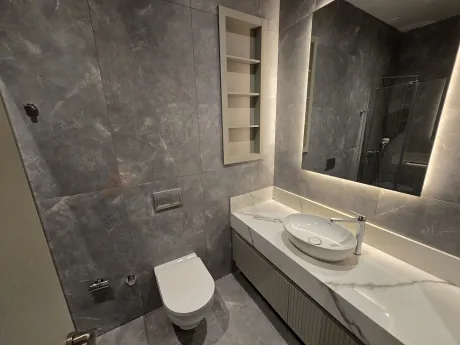 Modern bir dairenin şık tasarımlı banyo iç mekanı ve vitrifiye detayları.