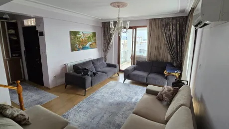 Modern tasarımlı, geniş pencereli ve gün ışığı alan ferah bir oturma odası görünümü.