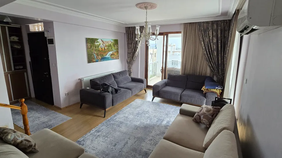 Modern tasarımlı, geniş pencereli ve gün ışığı alan ferah bir oturma odası görünümü.