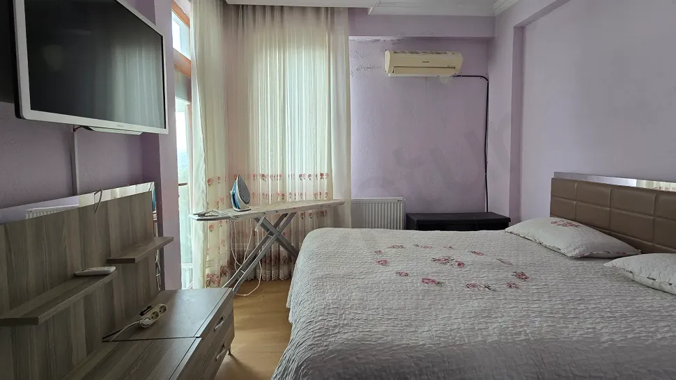 Bodrum'da deniz manzaralı bir dubleks dairenin geniş ve gün ışığı alan yatak odası görseli.