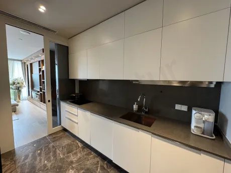 Modern tasarımlı, şık mutfak dolapları, tezgah ve mobilyaların bulunduğu aydınlık bir mutfak alanı.