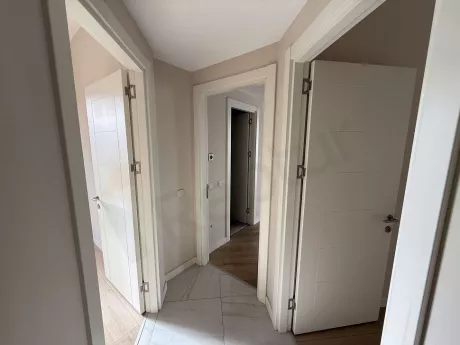 Modern bir binada yer alan geniş ve aydınlık daire koridoru görünümü.