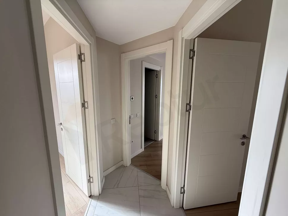 Modern bir binada yer alan geniş ve aydınlık daire koridoru görünümü.
