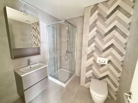 Modern tasarımlı, şık seramik döşemeli ve geniş aynalı yeni bir banyo iç mekanı.